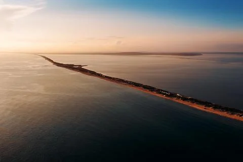 Long spit with sandy beach between sea and liman at sunset, aerial view from Stock Photos