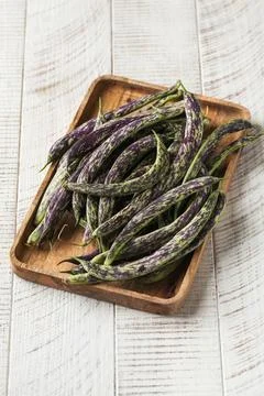 Long spotted stringed raw beans on a wooden background. Vegetables. Stock Photos