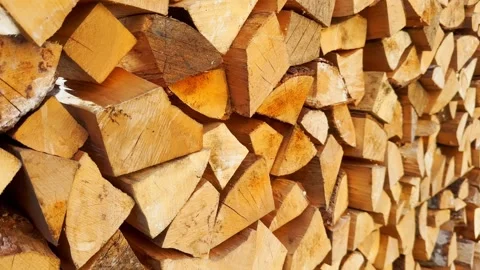 Long stack of split firewood in bright sunlight, showing golden log ends, cut Stock Footage 336472630