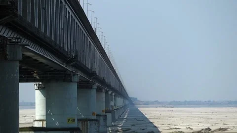 Long steel truss bridge with repeating pillars over wide riverbed Stock Footage 330708238