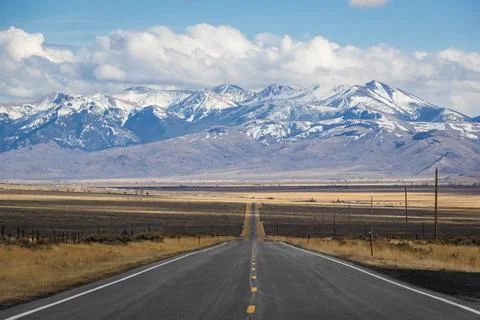 A long, straight road heading into the distant mountains Fotos de archivo