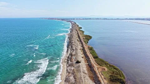 Long stretch of coastline with waves and land merging at the horizon near a Stock Footage 344779034