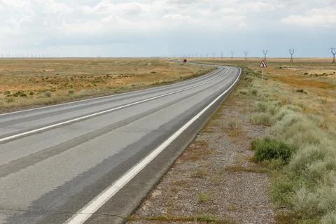 A long stretch of highway winds through the vast steppe of Kazakhstan, showca Stock Photos