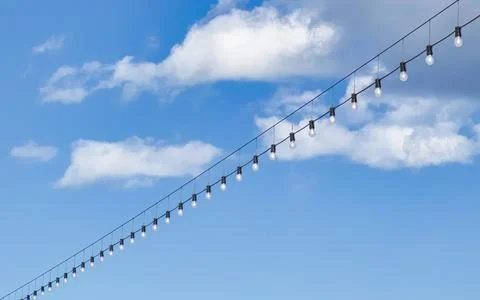 Long String of Incandescent Bulbs Hanging Against a Bright Blue Sky with Fl.. Stock Photos
