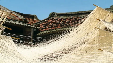 Long strings of noodles hang outside in the sunlight to dry. Traditional Stock Footage 137366177
