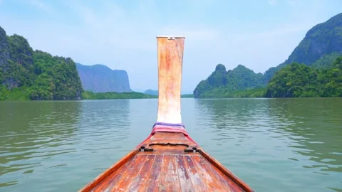 Long-tail boat cruising through a tropical bay with limestone cliffs. Video stock 333621291