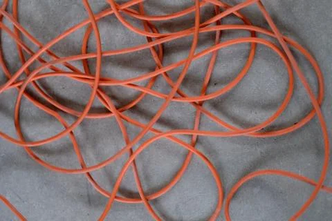 A long tangled electrical cable on a gray concrete floor Stock Photos