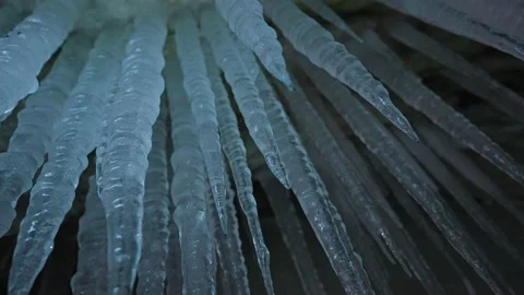 Long tapering white icicles with sharp edges hang on ceiling inside ice cave Stock Footage 166567043
