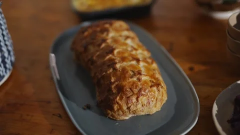 A long, thin pastry sits on a blue plate on a wooden table Stock Footage 295370728