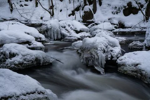 Long time exposure of water floating in a cold river in winter with ice and snow Stock Photos