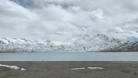 Long time lapse of clouds over turquoise lake and snow mountains Video stock 333809583