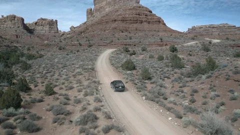 Long tracking shot of car on dangerous desert adventure dirt road Stock Footage 124888403