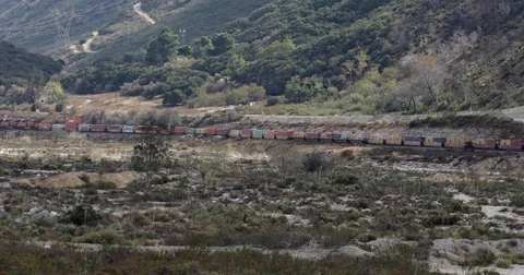 Long train across desert valley 4k 24fps Stock Footage 83495427
