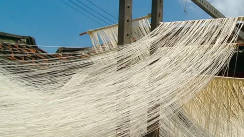 Long, uncut strands of raw noodles hang outside to dry using traditional Stock Footage 137366152