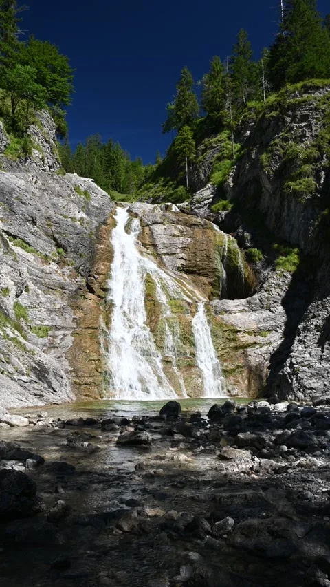 Long vertical shot of a waterfall with ponds in the Bavarian Alps in summer Stock Footage 260877233