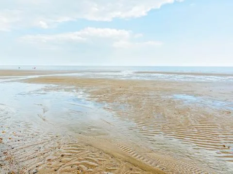 Long walk down the beach to the distant sea at low tide Foto stock