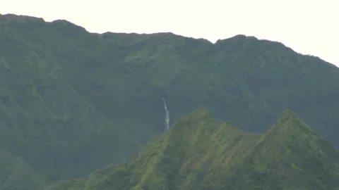 Long waterfall flows down large island mountain B Stock Footage 125340491