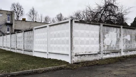 Long weathered concrete fence sections with geometric patterns and peeling white Vídeo Stock 344845578