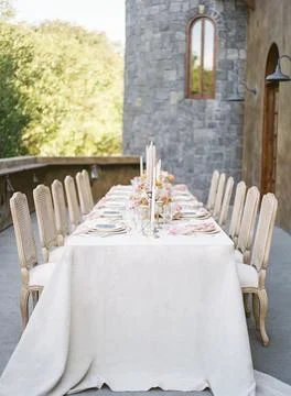 Long wedding reception table with white cloth cover with trees in the background Stock Photos