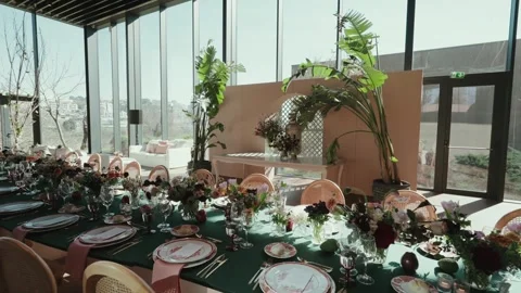 Long wedding table with floral decorations in bright indoor venue Stock Footage 333107832