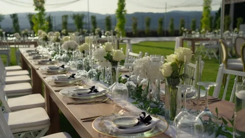 Long Wedding Table With White Roses And Gold Place Settings On A Lawn Stock Footage 340595633