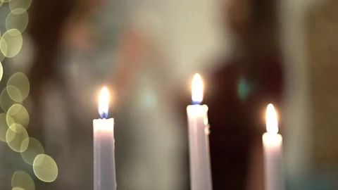 Long white candles burning, close-up. Women silhouettes on background Vídeo Stock 83259543