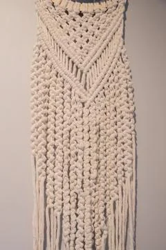 Long white macrame wall hanging with geometric patterns displayed Stock Photos