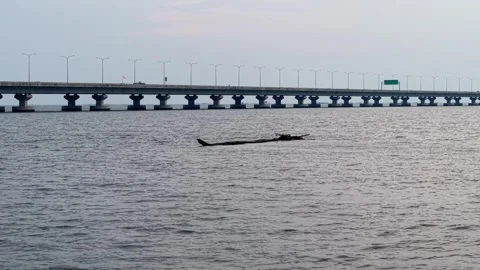 Long wide bridge with multiple pillars crossing calm water body under soft sky Stock Footage 341384644