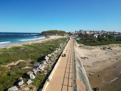 Long, winding road running parallel to an expansive beach and a clear, blue body Stockfoto's