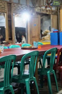 A long wooden dining table set with rows of green and red chairs Photos