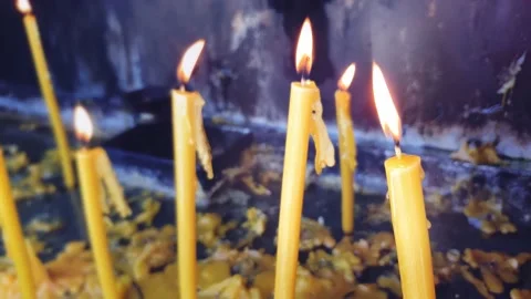 Long yellow candles burning on a candlestick and flooded with flowing wax. Stock Footage 148139031
