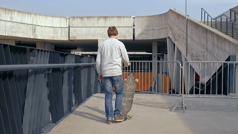 Longboarder picks up the longboard, walks down the stairs in the outer part of Stock Footage 90210018