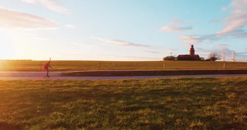 Longboarder skating on road through fields at sunset sidetracking aerial Stock Footage 153518959