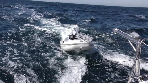 Longer shot of dinghy behind fast moving sailboat in heavy seas Stock Footage 68002727