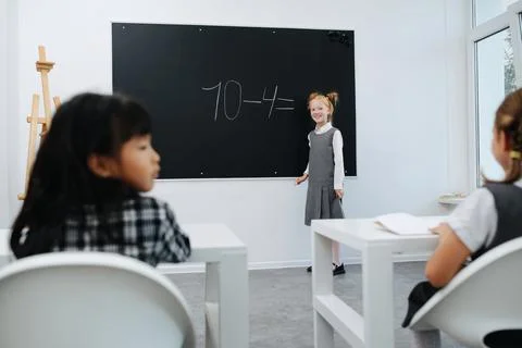 Longshot of a girl solving a basic math equasion on a blackboard in a class Foto stock