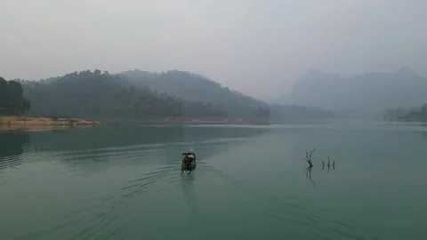 Longtail Boat Navigating Serene Misty Lake in Khao Sok, Thailand Video stock 335580190