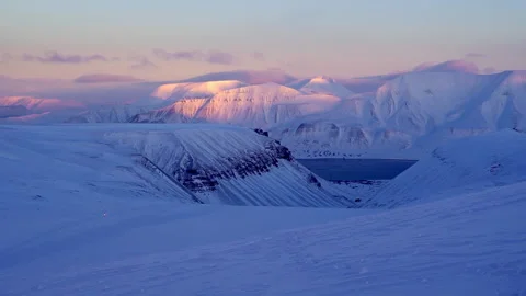 Longyearbyen The sun setting behind the snowy mountains on Svalbard. Video stock 230071682