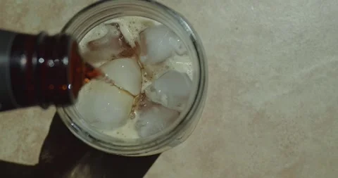 Look down at soda pouring into a cup with ice in slow motion Video stock 313161078