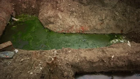 Look inside a large trench with rusty pipes and green water. Repair work of the Stock Footage 194395357