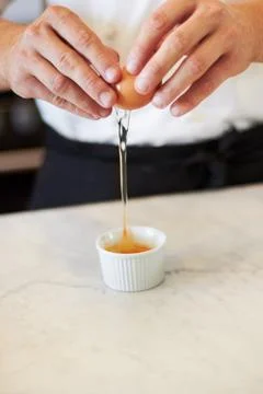 Look No shell pieces. A close up of a baker cracking his egg into a tiny Stock Photos