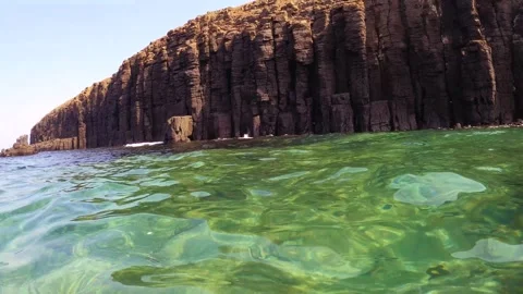 Look up from underwater to above ocean surface of north coast line of basalt sto Stock Footage 242326931