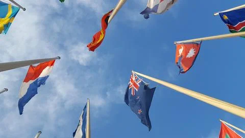 Look up view to the row of flags attached to the poles, over blue sky background Stock Photos