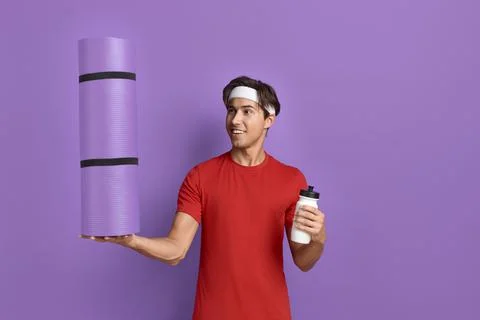 Look what I can do. Young funny sportsman holds fitness or yoga mat on palm a Stock Photos
