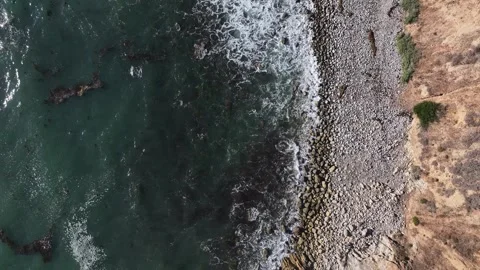 Looking above the moving ocean swaying back and forth along the coastline Stock Footage 337250564
