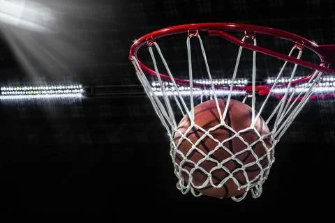 Looking up at a basketball falling through the net with arena lights Foto stock