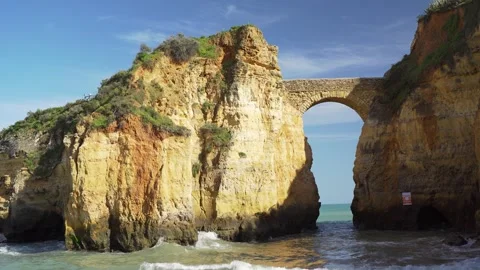 Looking up from beach to stone bridge over cliffs Stock Footage 273674293