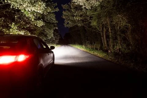 Looking behind a car parked on the side of the road on a mysterious night. Stock Photos