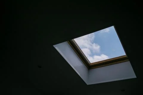 Looking up to the blue cloudy sky through modern square ceiling window Stockfoto's