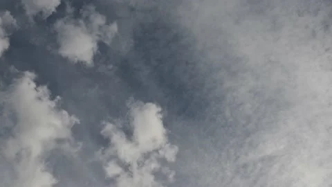Looking up into a blue sky filled with dramatic white and grey clouds.  Vídeo Stock 146386191