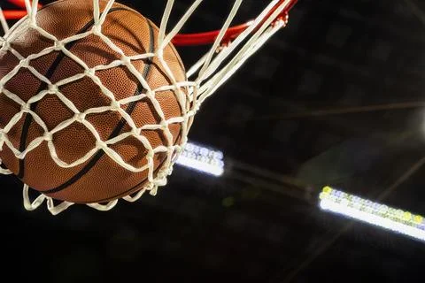 Looking up at the bottom of a basketball falling through the net with arena Foto stock